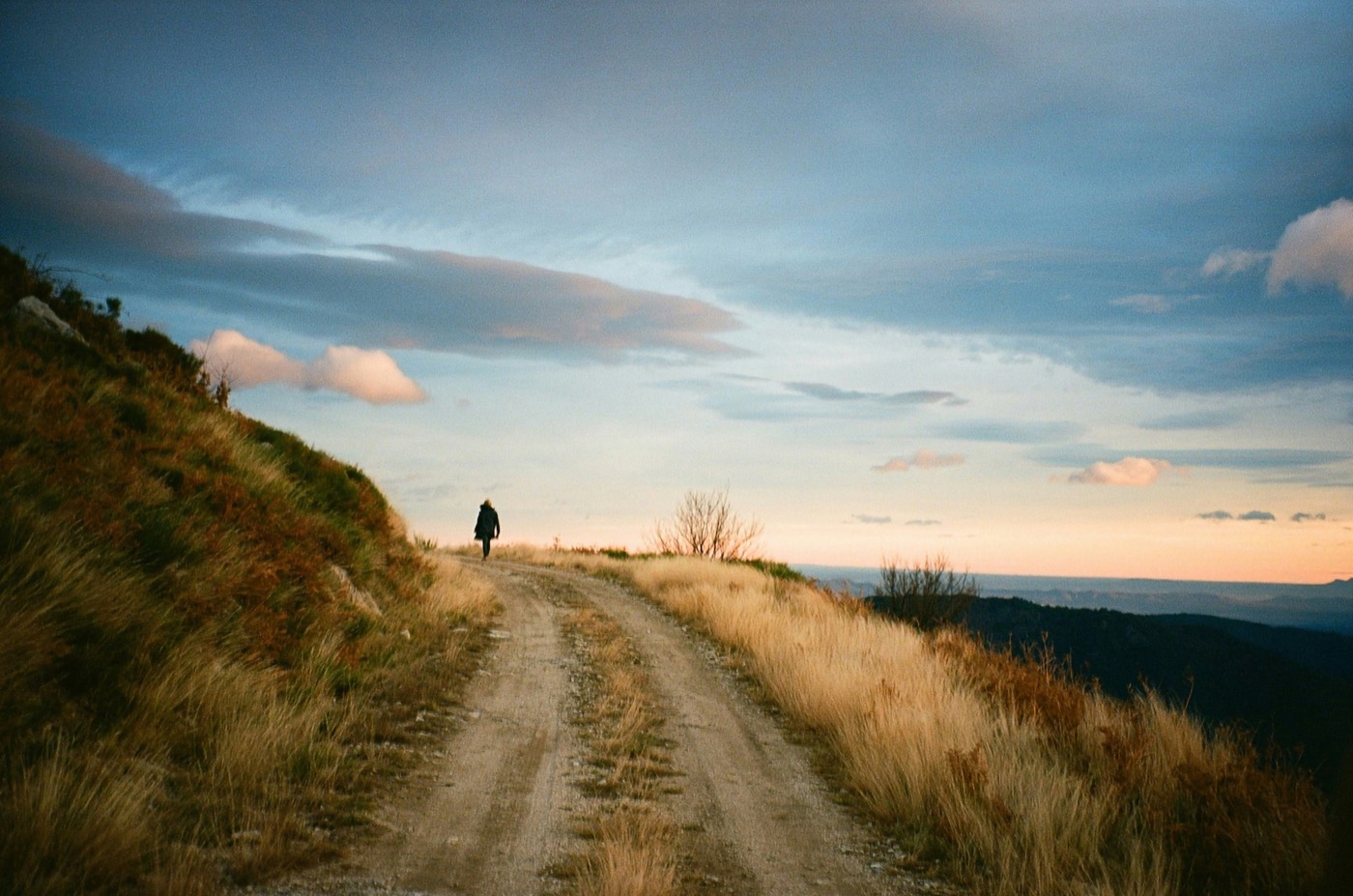 Una persona caminando por un sendero de montaña al atardecer