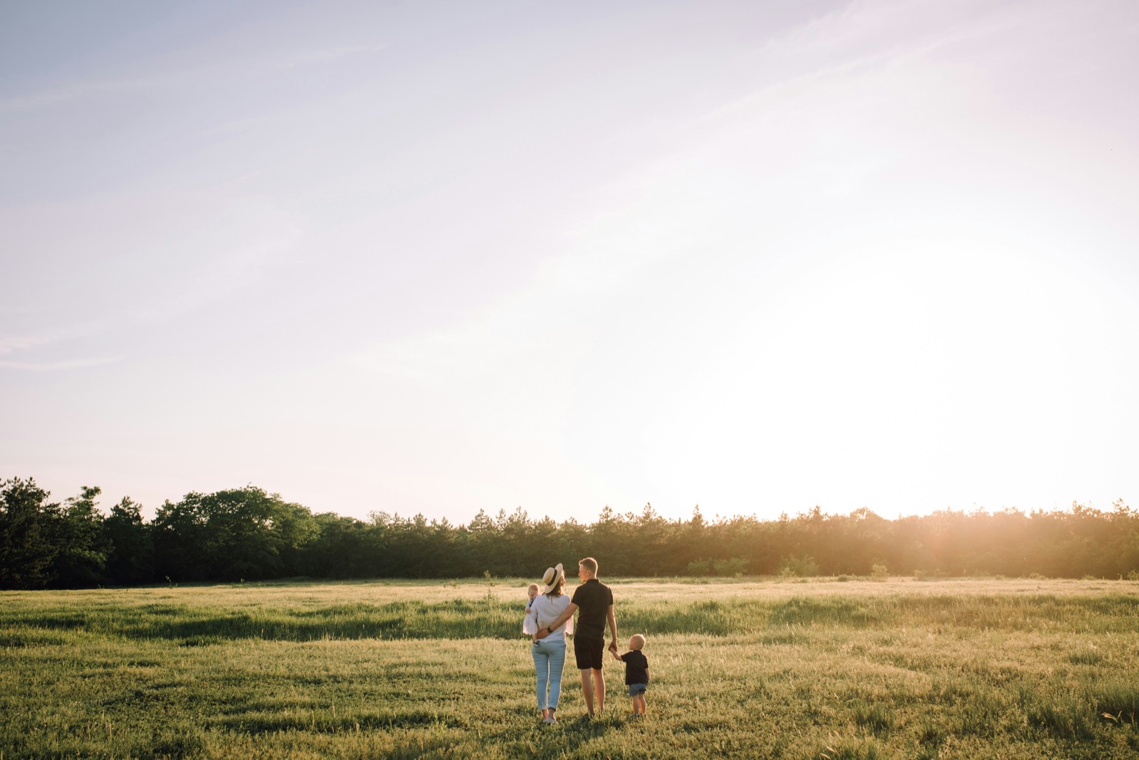 A family walking together across an open field at golden hour