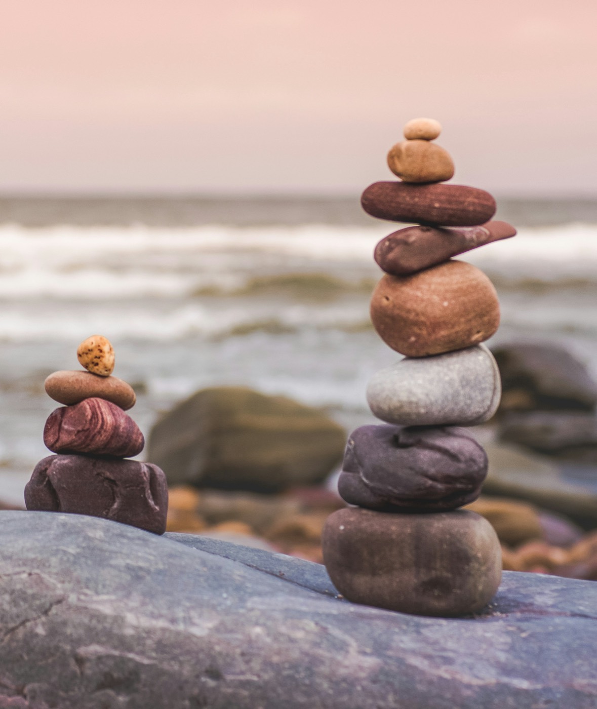 Balanced stacks of smooth stones on a beach at sunset
